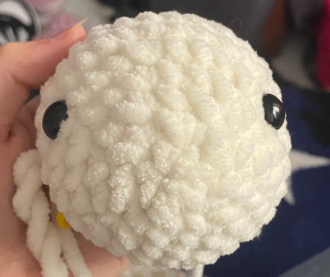 Close-up of crochet turtle head with safety eyes inserted between rounds.