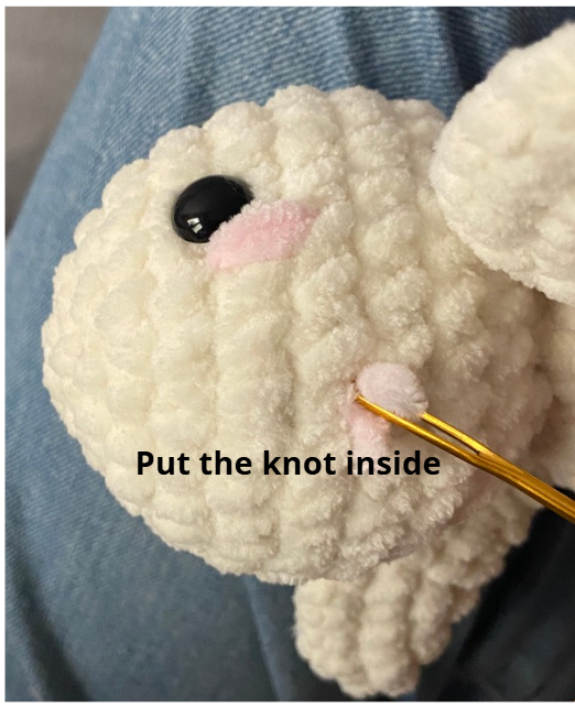 Close-up of crochet turtle head with safety eyes inserted between rounds and fiberfill stuffing visible.