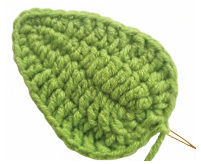 Crochet sunflower leaf in green yarn worked around a piece of floral shaping wire.
