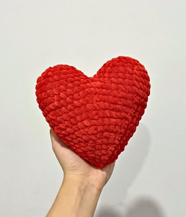 Crochet amigurumi red heart made with super bulky velvet yarn held in a hand, showing a soft, chunky, and seamless design.