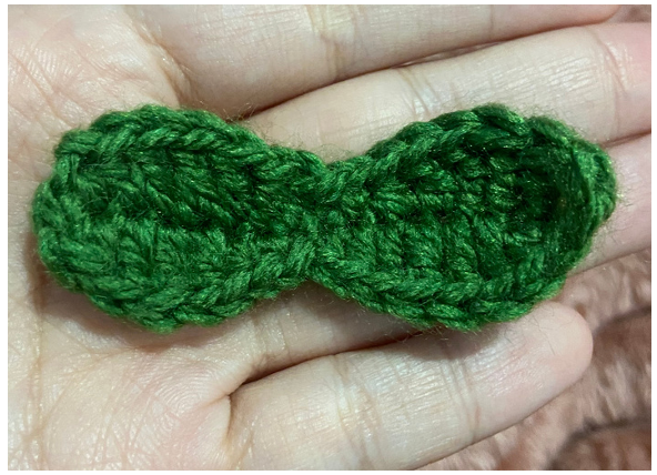 Crocheting green leaves and vine details for the amigurumi pumpkin car accessory.