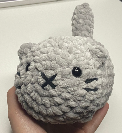 Finished grey plush loaf cat amigurumi made with chunky yarn and safety eyes