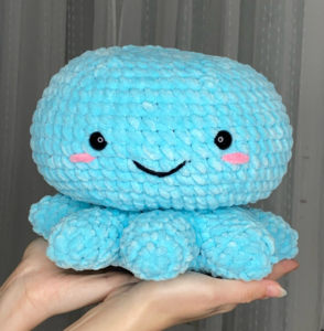 Finished handmade chunky crochet octopus toy with cute safety eyes and embroidered smile.