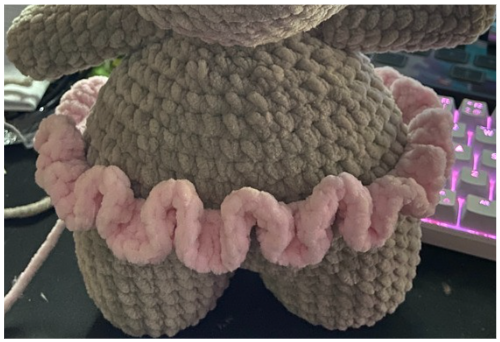 Close-up of the ruffled pink crochet tutu skirt wrapped around the handmade amigurumi hippo.