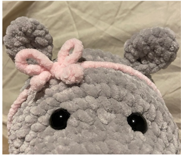 Close-up of the pink crochet hair bow tied neatly on top of the amigurumi hippo's head.