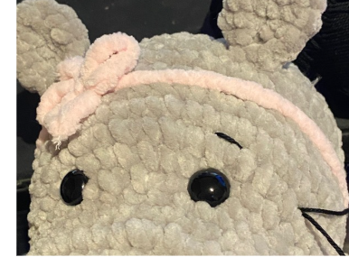 Close-up of the embroidered facial features, showing black cotton thread shaping the eyebrows and nostrils on the hippo's snout.