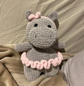 Finished Hippo amigurumi toy crocheted with chunky grey blanket yarn, featuring a pink tutu and a hair bow.