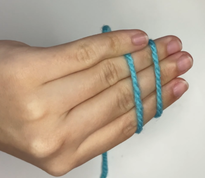 Wrapping the working yarn around left hand fingers to begin magic circle tutorial. Crossing the yarn over left fingers to create an X shape.