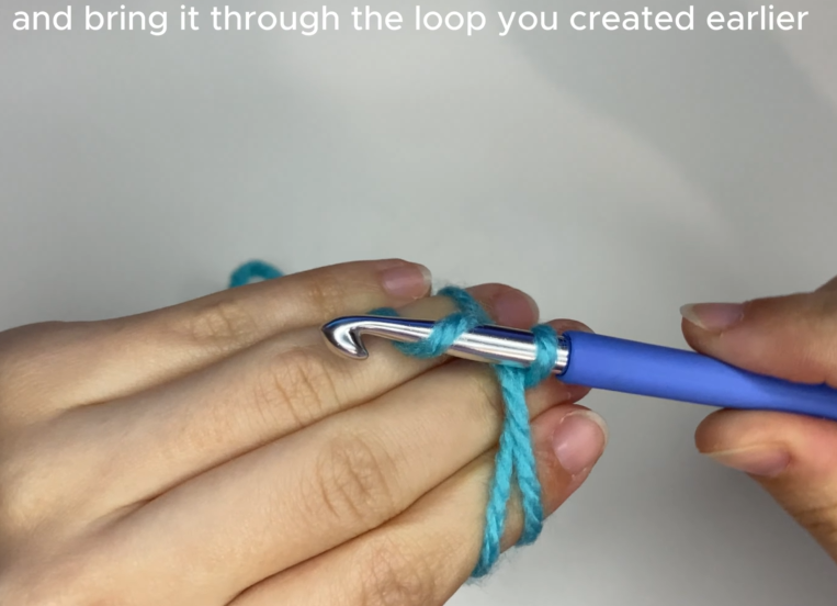Inserting crochet hook under and over yarn strands to create a magic circle loop.