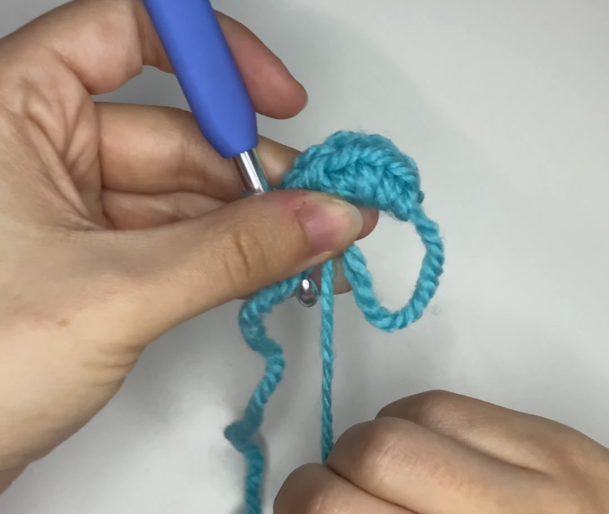 Gently pulling the yarn tail to close the magic ring completely for amigurumi.