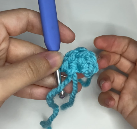 Gently pulling the yarn tail to close the magic ring completely for amigurumi.