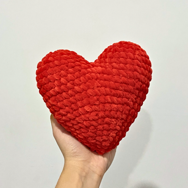 Crochet amigurumi red heart made with super bulky velvet yarn held in a hand, showing a soft, chunky, and seamless design.