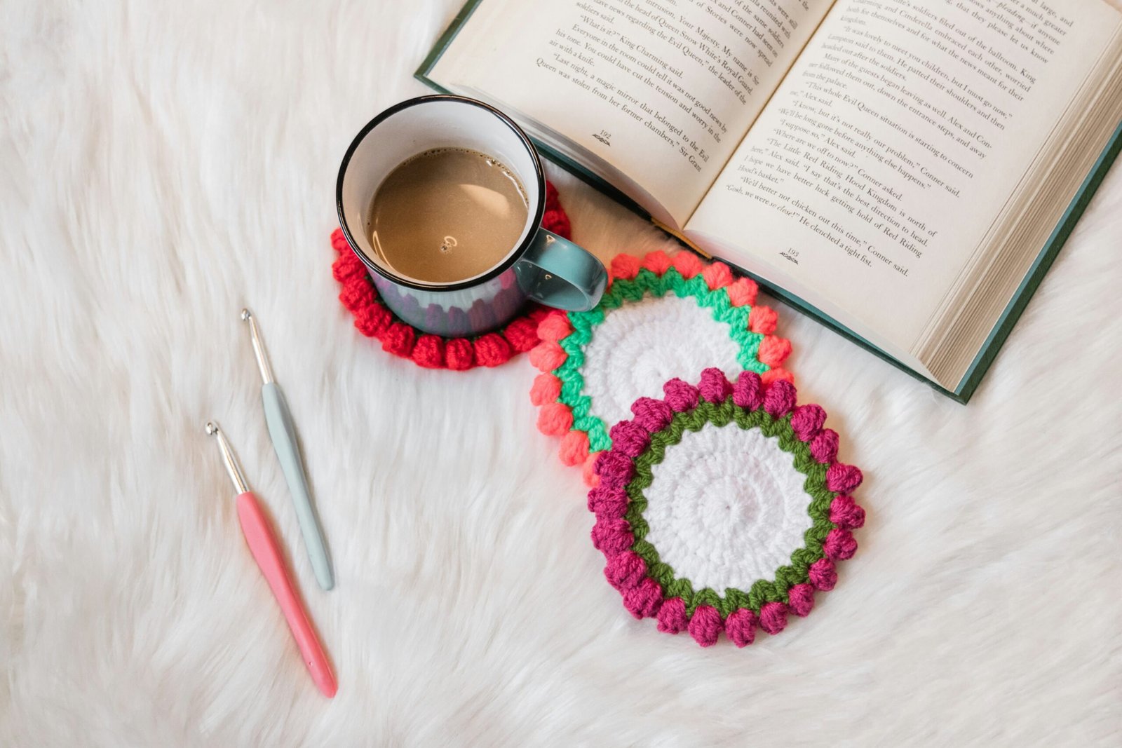 crochet coasters with some crochet hooks on a cozy desk with a coffee cup and an open book