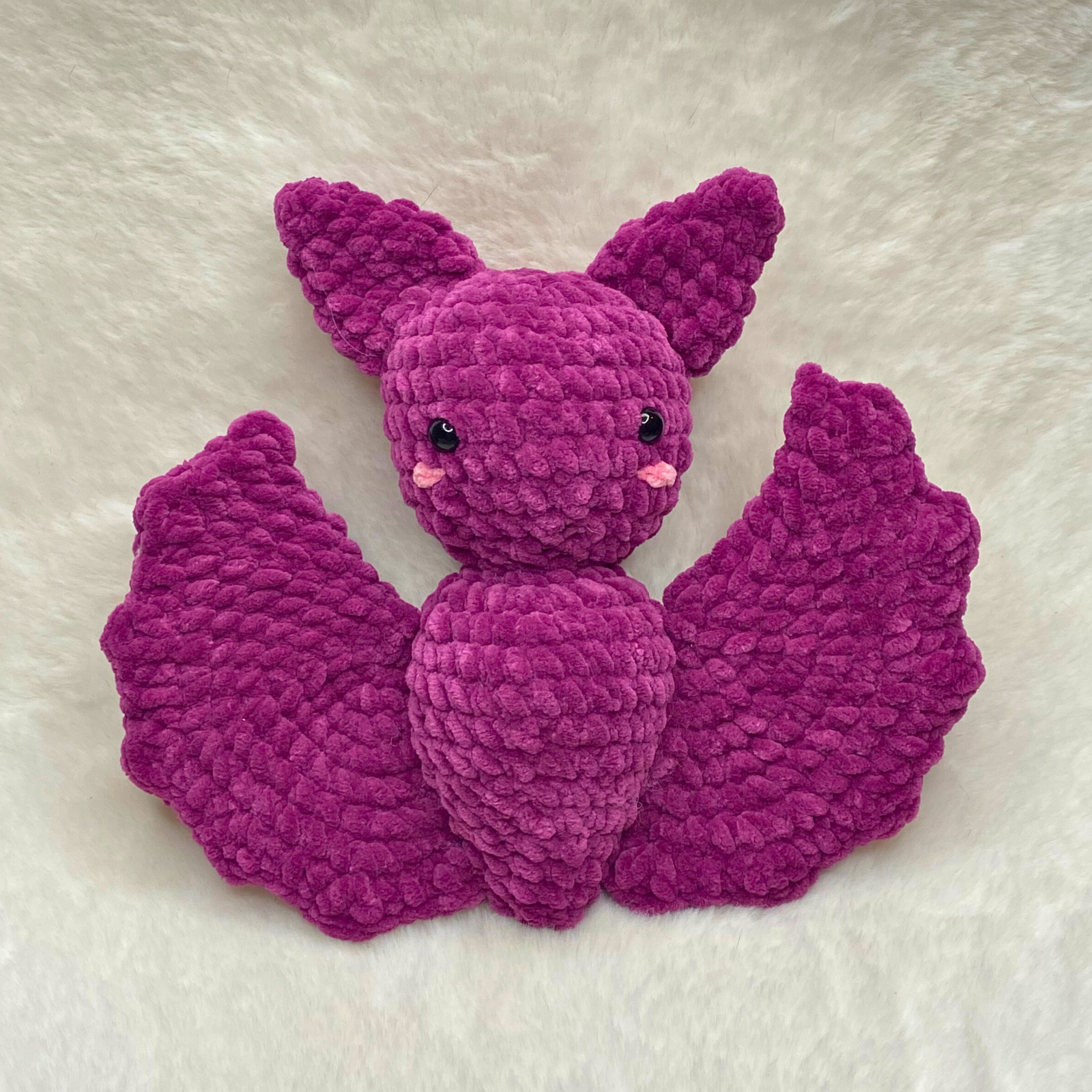 Handcrafted purple plush bat crochet amigurumi made with bulky chenille yarn, featuring big ears and spread wings against a clean background.