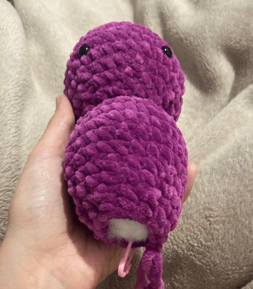 Crochet purple plush bat head and body in progress, showing stitched continuous rounds and safety eyes attached.