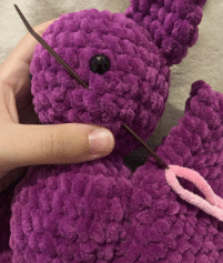 Sewing process of attaching the ears and wings to the stuffed plush bat amigurumi using a tapestry needle.
