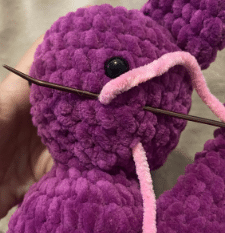Sewing process of attaching the ears and wings to the stuffed plush bat amigurumi using a tapestry needle.
