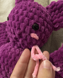 Sewing process of attaching the ears and wings to the stuffed plush bat amigurumi using a tapestry needle.