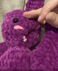 Sewing process of attaching the ears and wings to the stuffed plush bat amigurumi using a tapestry needle.