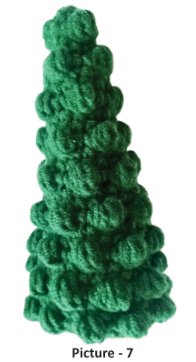 Handcrafted green bobble Christmas tree crochet amigurumi made with textured stitches against a neutral background.