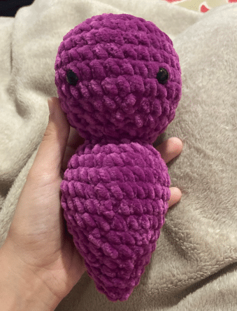 Crochet purple plush bat head and body in progress, showing stitched continuous rounds and safety eyes attached.