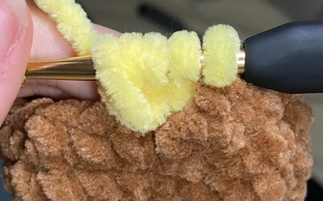 No sew crochet duck body showing yellow bobble stitch feet and continuous brown plush body.