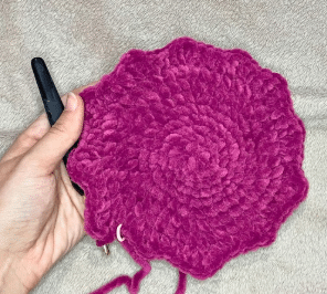 Two completed purple crochet bat wings folded in half, ready to be sewn onto the amigurumi plushie.