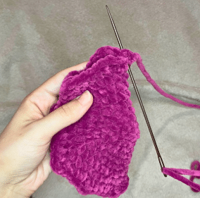 Two completed purple crochet bat wings folded in half, ready to be sewn onto the amigurumi plushie.