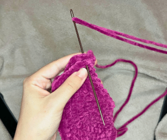 Two completed purple crochet bat wings folded in half, ready to be sewn onto the amigurumi plushie.