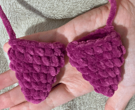 Pair of small pointed purple crochet bat ears made with plush yarn before assembly.