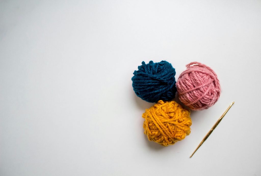 colorful crochet yarn and a crochet hook on a white desk